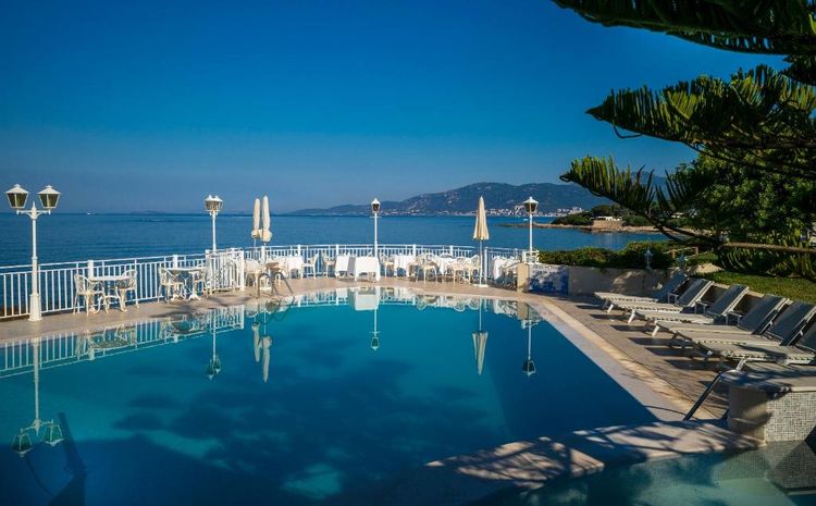 Der Pool und seine Liegestühle mit Blick auf das Meer