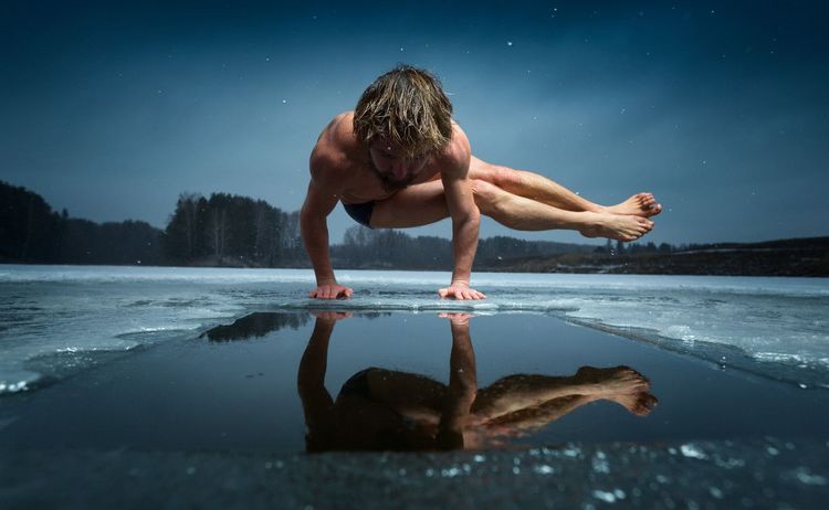 Un homme pratique le yoga du froid sur un lac gelé.