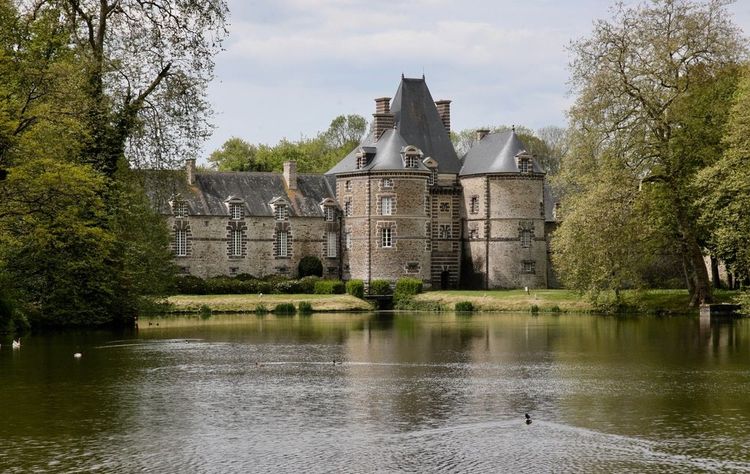 L'extérieur du château de Canisy bordé par un plan d'eau