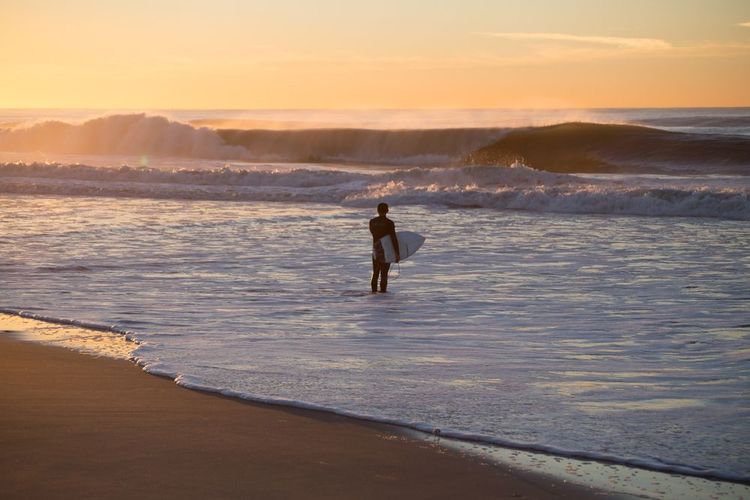 Un surfer sur la plage de Rockaway Beach à New York, Etats-Unis