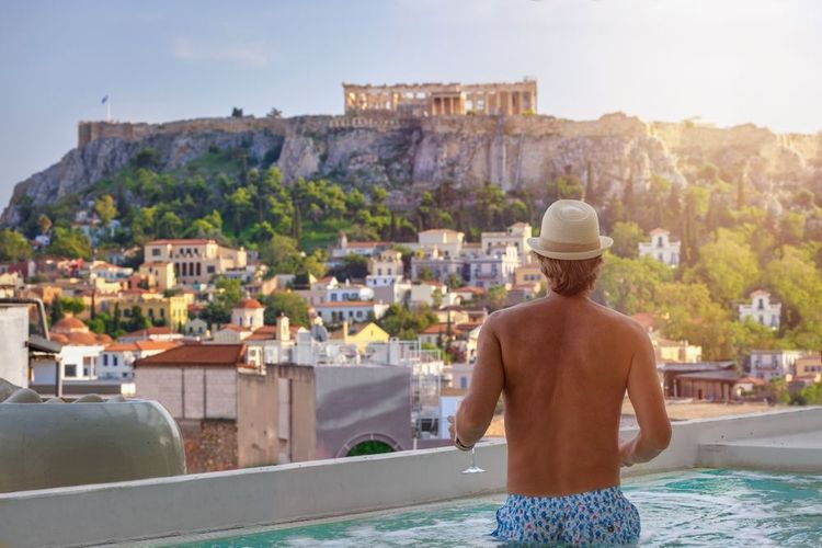 Un touriste dans une piscine ombragée avec vue sur l'Acropole d'Athènes, Grèce