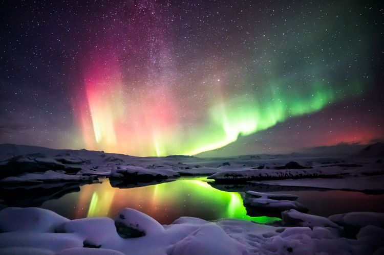 Une belle aurore verte et rouge dansant sur la lagune de Jokulsarlon, en Islande.