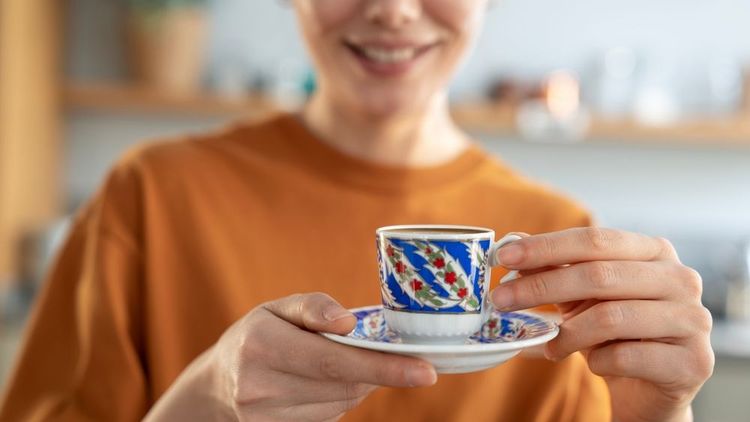 Une femme qui propose une tasse de café