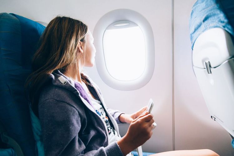 Une femme regardant par le hublot d'un avion