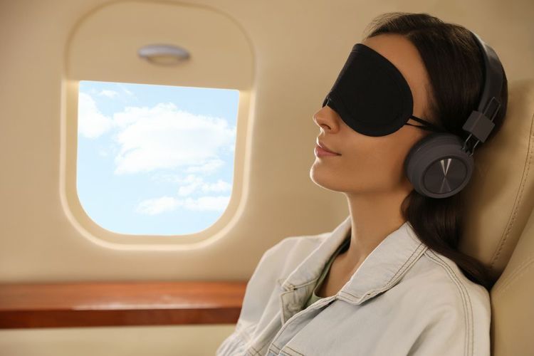 Une jeune femme dans l'avion avec son masque et son casque