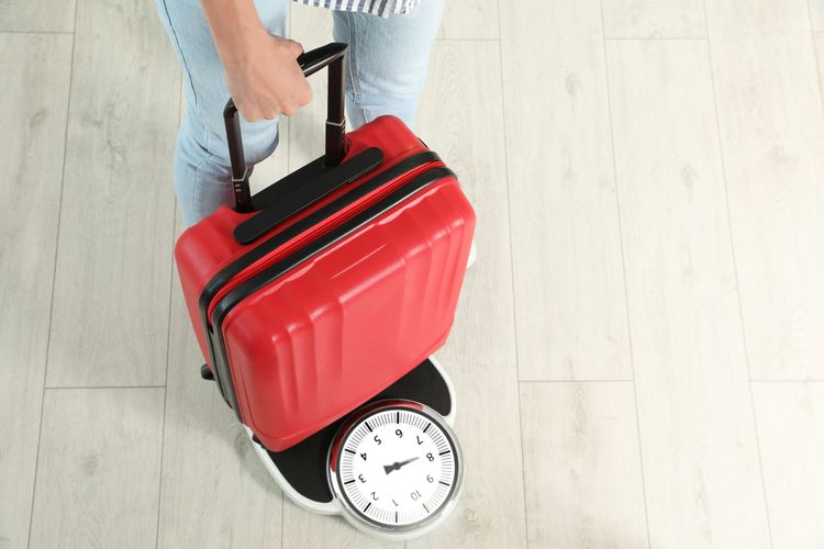 Une personne qui se pèse avec sa valise