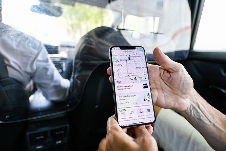 Usager à l'arrière d'un VTC vérifiant son trajet sur l'application