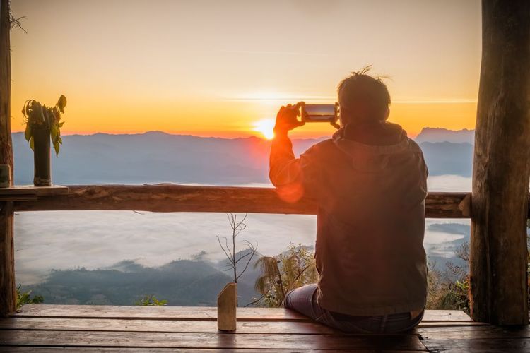 Un homme prenant en photo la nature au lever du soleil.