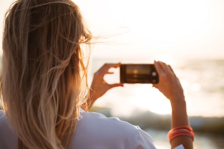 Une femme photographie le coucher du soleil.