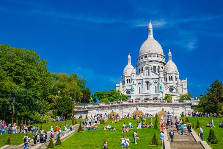 la célèbre église de Montmartre à Paris, France, une journée d'été, entourée de nombreux touristes sur les escaliers.