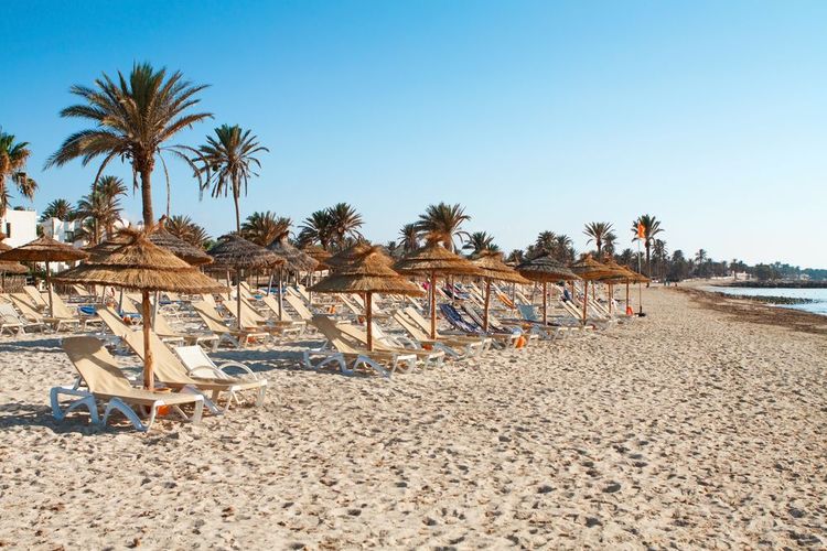 Plage aménagée avec transats et parasols au coucher du soleil