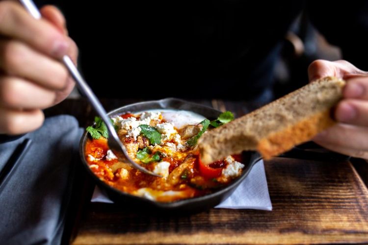 Délice des œufs pochés de la shakshuka dans une préparation de tomates, poivrons et oignons épicée