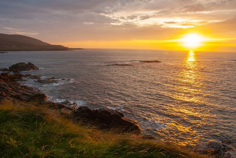 Coucher de soleil orange sur littoral rocheux de l'île de Barra, Écosse