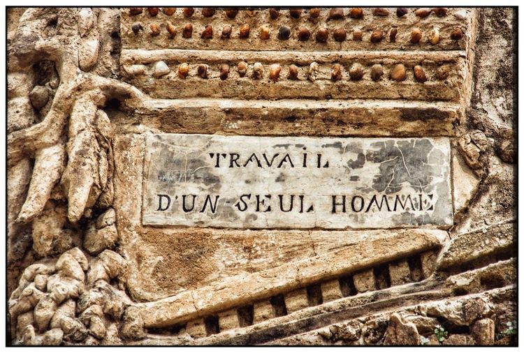 La phrase "travail d'un seul Homme", gravée dans une des pierres du palais.