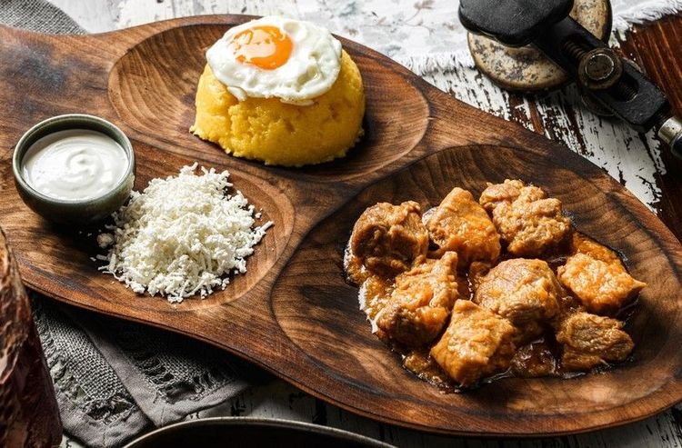 Cuisine traditionnelle roumaine : polenta (mamaliga) avec oeufs au plat, fromage, viande et crème aigre