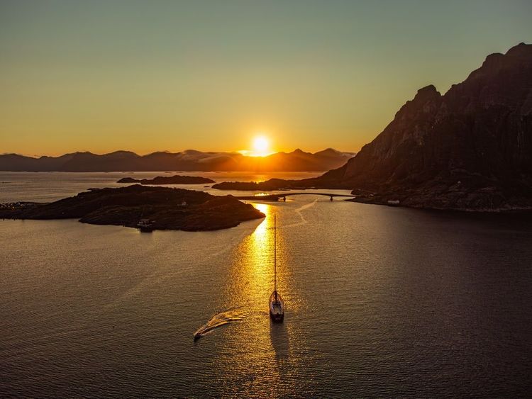 Un voilier navigue sous le soleil de minuit dans les eaux des îles Lofoten.