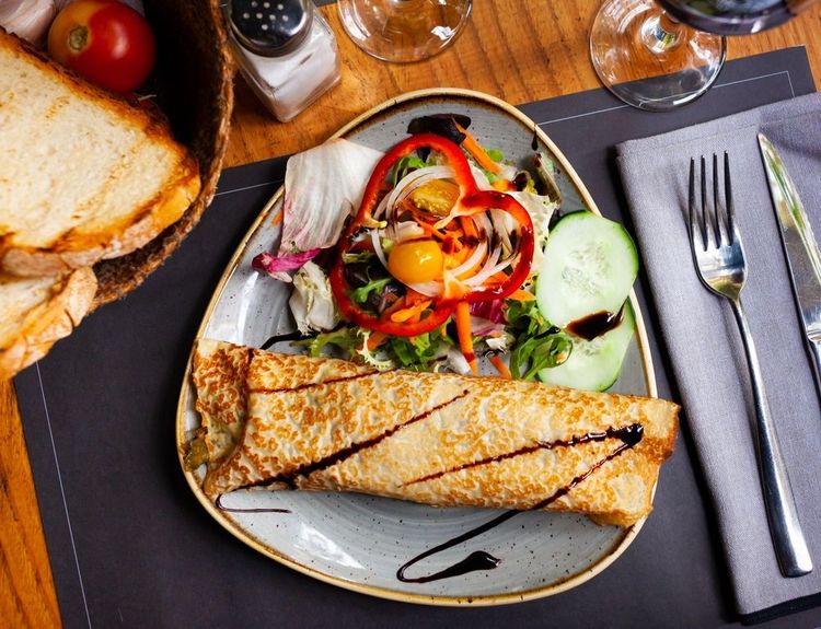 Brunch bulgare avec des crudités, une crèpe, un œuf au plat et du pain grillé