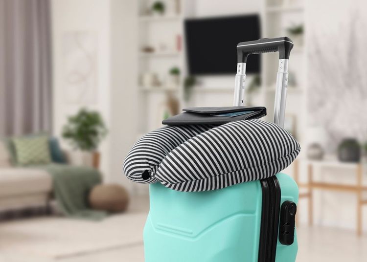 Un oreiller de voyage sur une valise bleue.