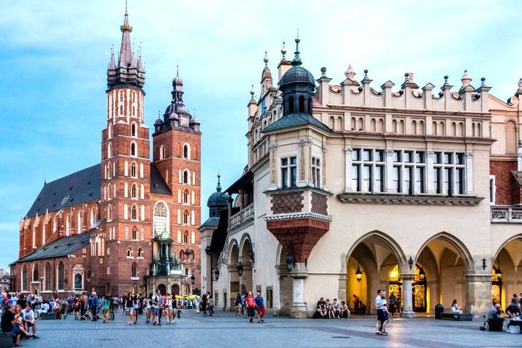 La basilique gothique de Sainte-Marie (à g.) et le Sukiennice ou «Halle aux Draps" (dr.) sur la place Rynek Główny, place du marché, à Cracovie.