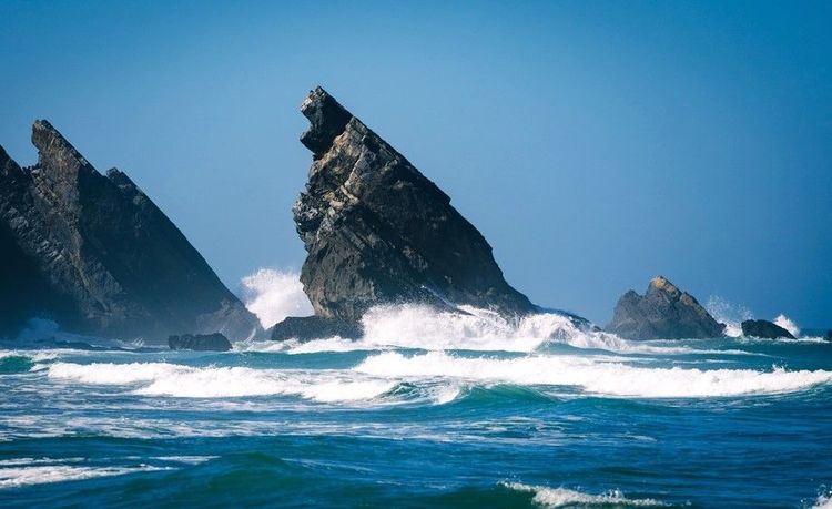A Praia da Adraga, des pics puissants sortent de l'eau