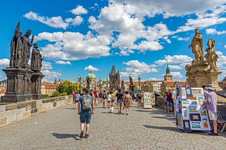 Artistes, touristes et statues baroques sur le pont Charles à Prague