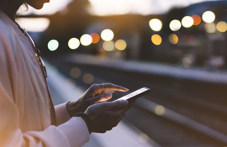 Une femme qui utilise son téléphone en attendant son train