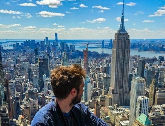 Un homme collé à la baie vitrée de The Summit regarde Manhattan et l'Empire State Building